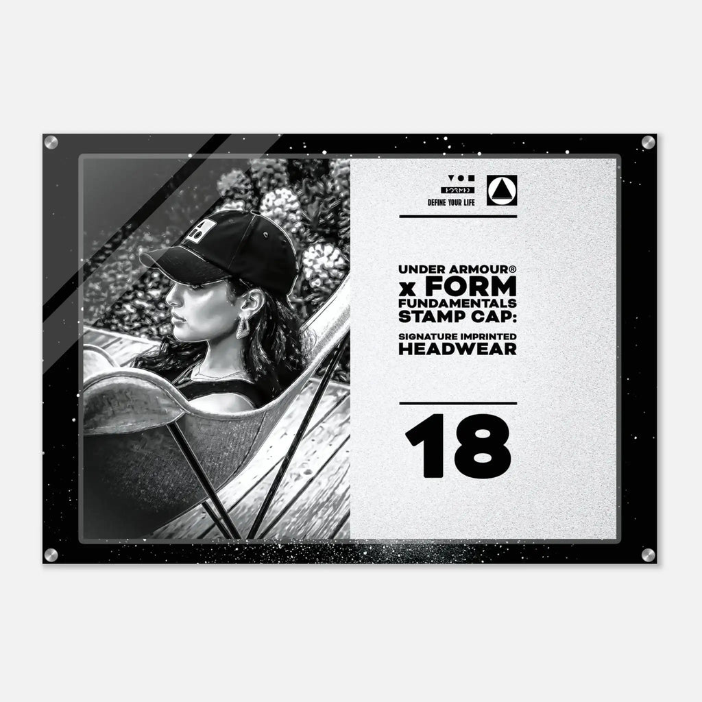 A rectangular black-and-white promotional print or poster featuring a woman in a baseball cap on the left and text on the right including 'UNDER ARMOUR x FORM FUNDAMENTALS STAMP CAP' and the number 18. The print is shown against a light gray background with a subtle drop shadow.