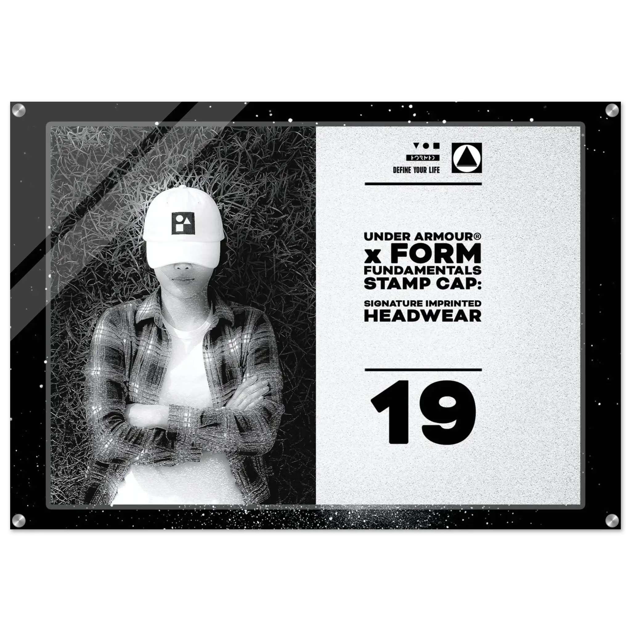 A rectangular acrylic wall art print featuring a black-and-white photo of a person wearing a white Under Armour cap, alongside product text that reads 'UNDER ARMOUR x FORM FUNDAMENTALS STAMP CAP: SIGNATURE IMPRINTED HEADWEAR' and the number '19'.