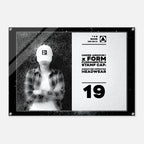 A rectangular acrylic wall art print with a black frame and corner screws, featuring a black-and-white split design. The left side shows a grayscale photo of a person wearing a white cap, and the right side has text reading 'UNDER ARMOUR x FORM FUNDAMENTALS STAMP CAP SIGNATURE IMPRINTED HEADWEAR' with the number 19.