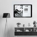 A black-framed poster print hanging on a light gray wall above a white and dark wood media console. The poster features a black-and-white photo of a person wearing a cap and bold text from Form Finding Design.