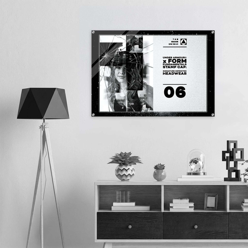A black-framed wall art print with a black-and-white graphic design hangs on a light gray wall above a white and dark wood shelf. The print includes text reading from Form Finding Design.