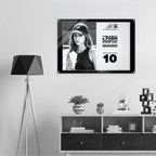 A framed black-and-white poster hanging on a light gray wall above a white and dark wood console shelf, with a black tripod floor lamp on the left. The poster features a black-and-white portrait of a woman in a cap and bold text from Form Finding Design.