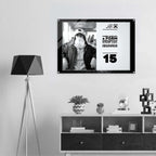 A framed black-and-white poster hangs on a light gray wall above a white and dark wood console shelf, next to a black geometric floor lamp. The poster features a seated person wearing a face mask and text from Form Finding Design (FormFD).