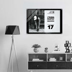A black-framed wall art print hanging above a white shelf in a modern room. The print features a black-and-white photo of a person tying shoes next to bold text from Form Finding Design (FormFD).
