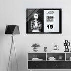 A framed black-and-white poster or print hangs on a light gray wall above a white shelf with decorative objects. The poster shows a split design: a black-and-white photo of a person wearing a cap on the left, and bold text from Form Finding Design (FormFD).