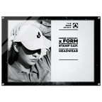 A black-framed promotional display sign featuring a black-and-white photo of a person wearing a white Under Armour cap on the left, and printed text on the right that reads 'UNDER ARMOUR x FORM FUNDAMENTALS STAMP CAP: SIGNATURE IMPRINTED HEADWEAR' with the Under Armour logo. The sign is photographed against a plain white background.