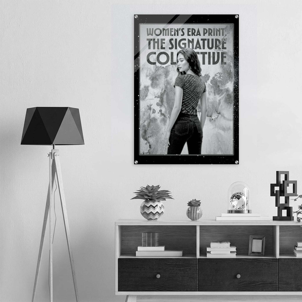 Framed poster of a woman with text on a wall above a shelf with decor items.