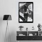 Poster of a woman looking at a mirror on a wall above a shelf with decor items.