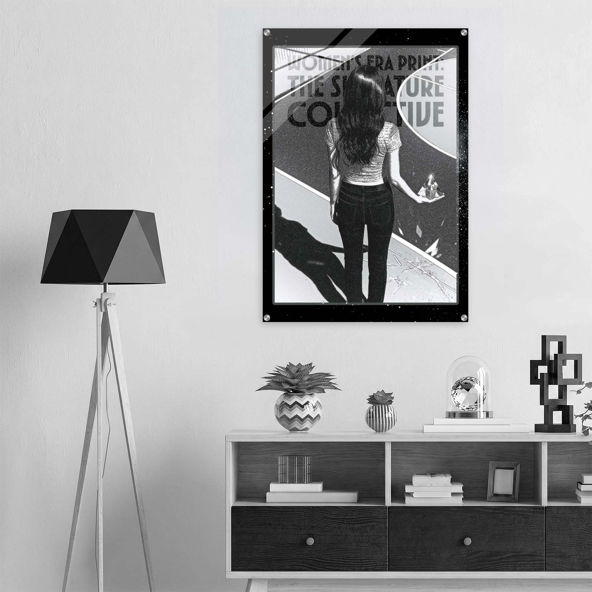 Poster of a woman looking at a mirror on a wall above a shelf with decor items.