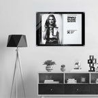 Framed poster of a woman on a wall above a shelf with decorative items.