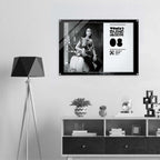 Framed poster of a woman with a motorcycle on a wall above a shelf with decorative items.