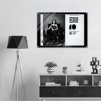 Framed poster on a wall above a shelf with decorative items