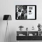 Framed photo of a woman standing outdoors on a wall above a shelf with decorative items.