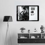 Framed artwork on a wall above a shelf with decorative items