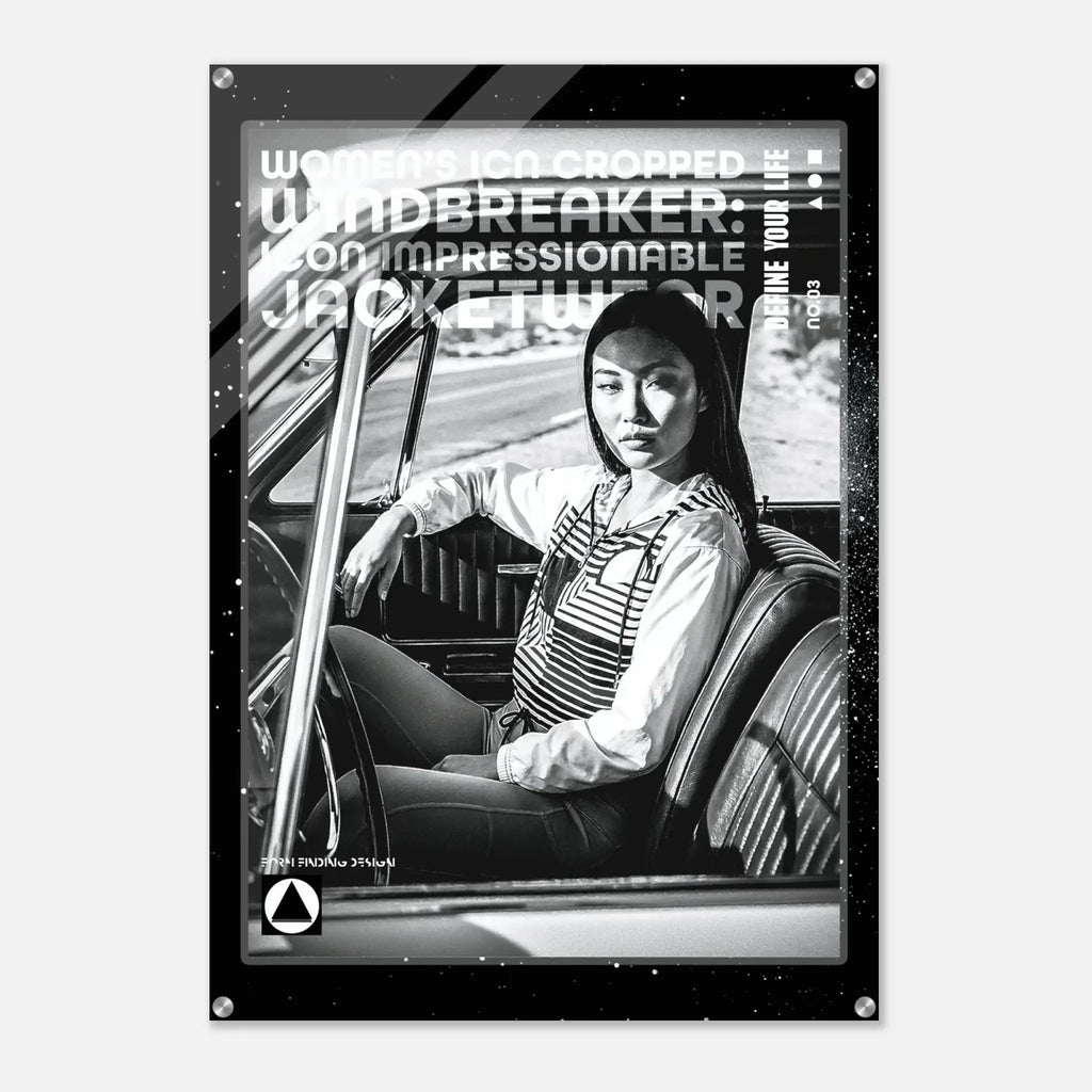 A black and white poster print featuring a woman sitting in a car interior, with bold text overlays including 'WOMEN'S ICON CROPPED WINDBREAKER: ICON IMPRESSIONABLE JACKETWEAR' and 'DEFINE YOUR LIFE.' The poster is shown hanging against a light gray wall.