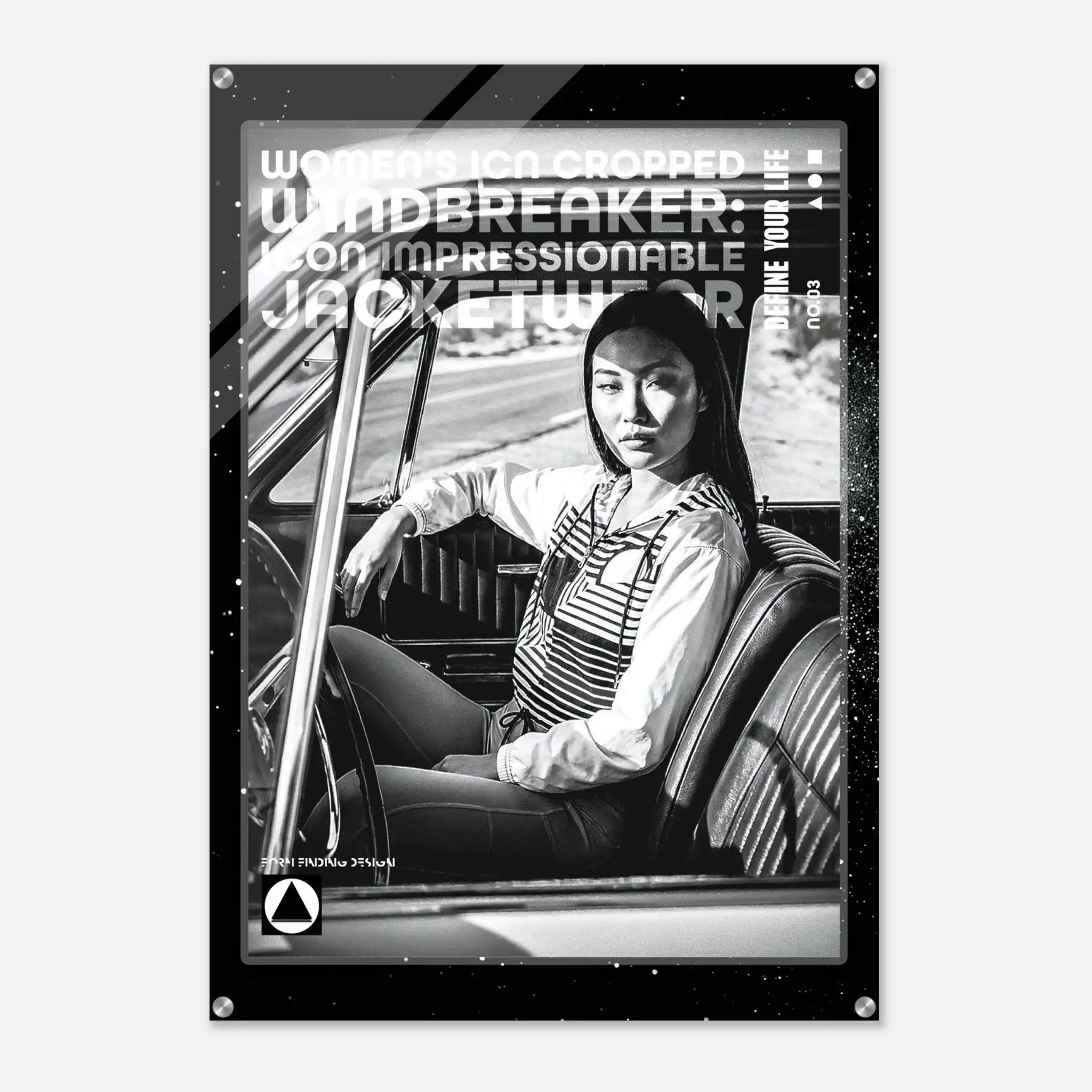 A black and white poster print featuring a woman sitting in a car interior, with bold text overlays including 'WOMEN'S ICON CROPPED WINDBREAKER: ICON IMPRESSIONABLE JACKETWEAR' and 'DEFINE YOUR LIFE.' The poster is shown hanging against a light gray wall.