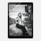 A black-framed poster or print featuring a black-and-white photo of a woman sitting on a rock outdoors, with large text reading 'WOMEN'S ICON CROPPED WINDBREAKER ICON IMPRESSIONABLE JACKETWEAR' and a small logo at the bottom.