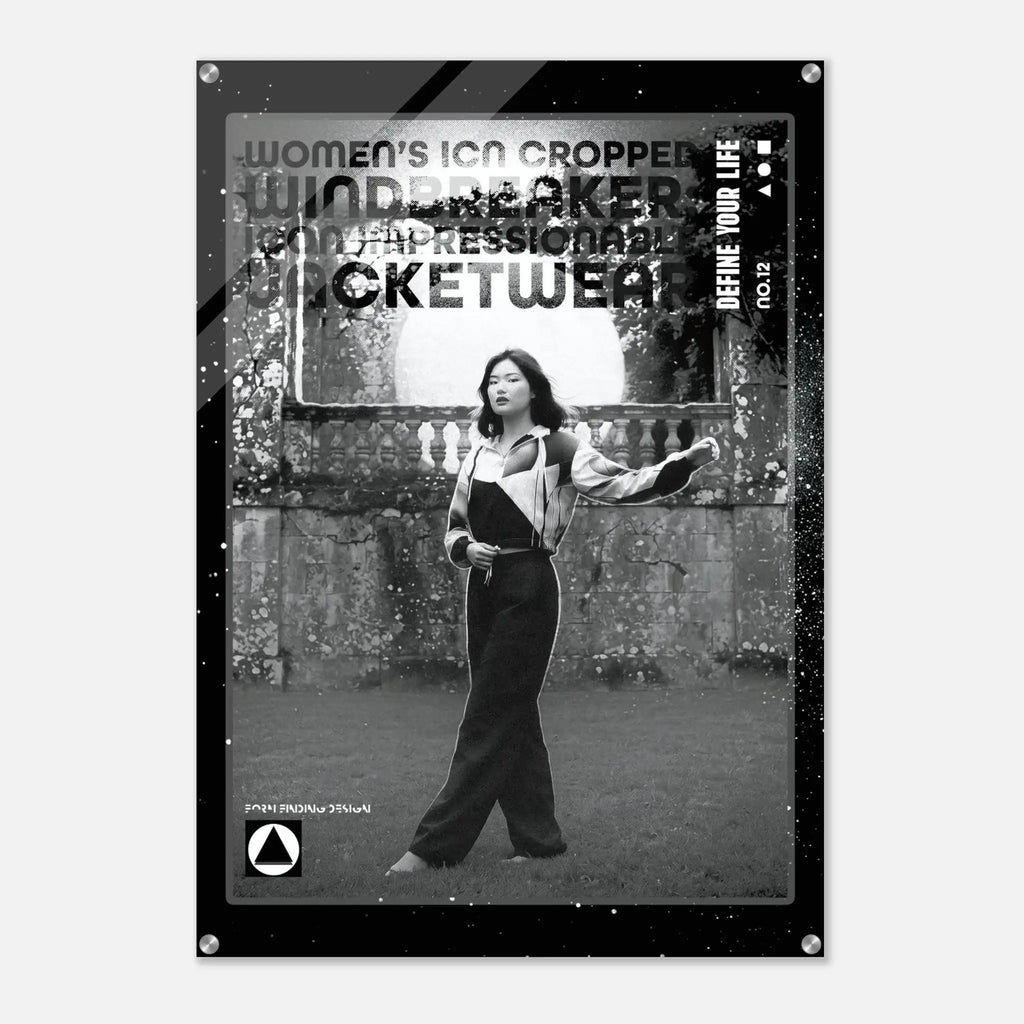A black and white fashion poster featuring a cropped photo of a woman in a jumpsuit, with bold distressed text including 'WOMEN'S ICON CROPPED WINDBREAKER'. The poster is shown hanging against a light gray wall.