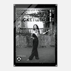 A black and white fashion poster featuring a cropped photo of a woman in a jumpsuit, with bold distressed text including 'WOMEN'S ICON CROPPED WINDBREAKER'. The poster is shown hanging against a light gray wall.