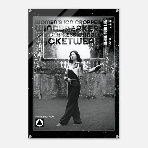 A black and white fashion poster featuring a cropped photo of a woman in a jumpsuit, with bold distressed text including 'WOMEN'S ICON CROPPED WINDBREAKER'. The poster is shown hanging against a light gray wall.