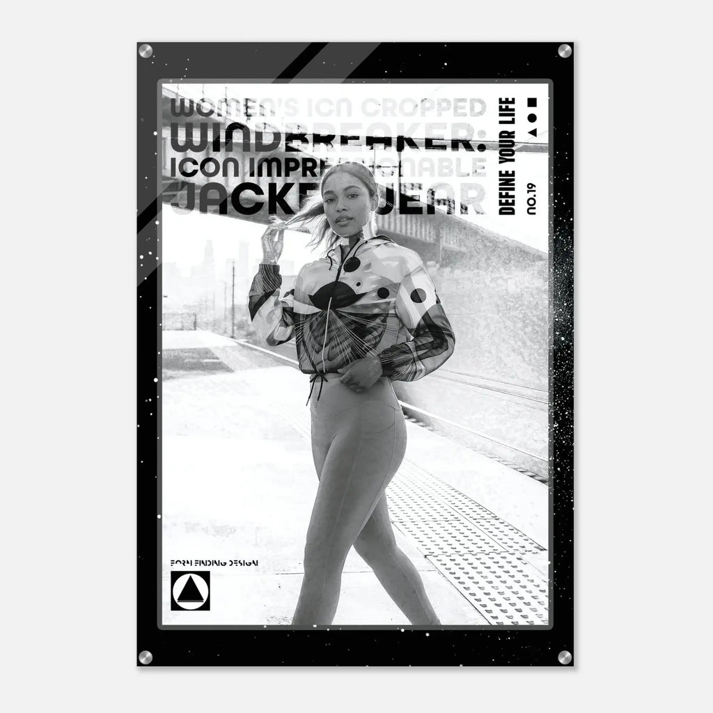 A black-framed poster or art print featuring a black-and-white fashion photograph of a woman on a train platform, with bold text overlays including 'WINDBREAKER', 'DEFINE YOUR LIFE', and 'NO.19'.