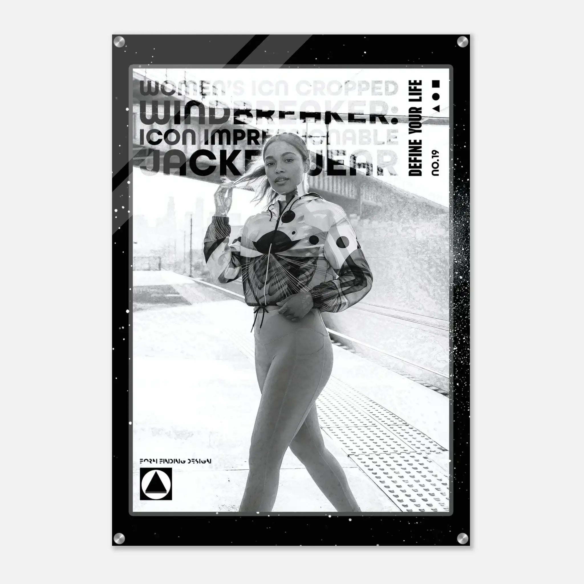 A black-framed poster or art print featuring a black-and-white fashion photograph of a woman on a train platform, with bold text overlays including 'WINDBREAKER', 'DEFINE YOUR LIFE', and 'NO.19'.