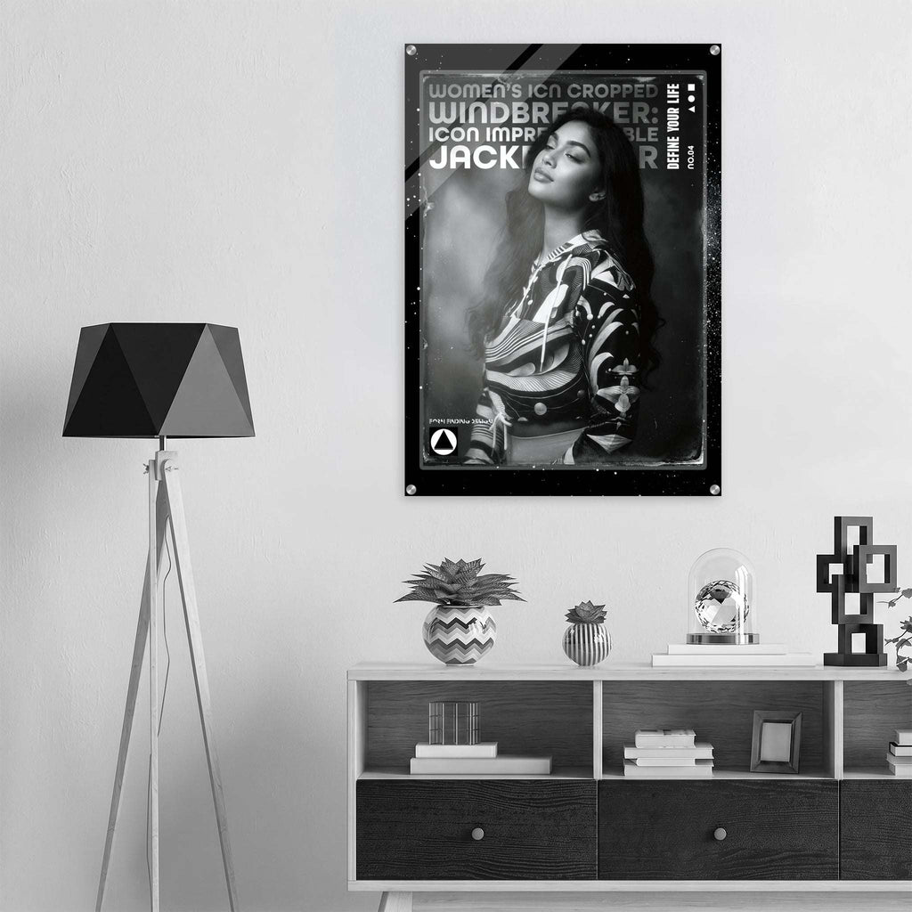A black and white poster of titled 'Women's Icon Cropped: Windbreaker Icon Impression', displayed on a light gray wall in a modern, minimalist room setting with a tripod floor lamp and a wooden shelf.
