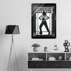 A black and white poster print of 'Windbreaker' jacket hanging on a white wall in a modern, minimalist room setting with a tripod floor lamp and a wooden shelf below.