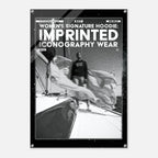 A black poster or print with a white border and text reading 'WOMEN'S SIGNATURE HOODIE: IMPRINTED ICONOGRAPHY WEAR' above a black-and-white photo of a person standing on a boat deck.