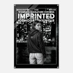 A black and white fashion poster featuring a woman from behind wearing a hoodie with a small circular logo on the back, set against a city skyline at night. The poster has a black border with the text 'WOMEN'S SIGNATURE HOODIE: IMPRINTED ICONOGRAPHY WEAR' and 'FORM FINDING DESIGN'.