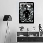 A black and white poster for the Women's Signature Hoodie 'Imprinted' is displayed on a light gray wall in a modern room setting above a wooden console table.