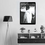 A black and white poster featuring a person in a hoodie hanging on a wall in a modern styled room with a tripod floor lamp and a low cabinet.