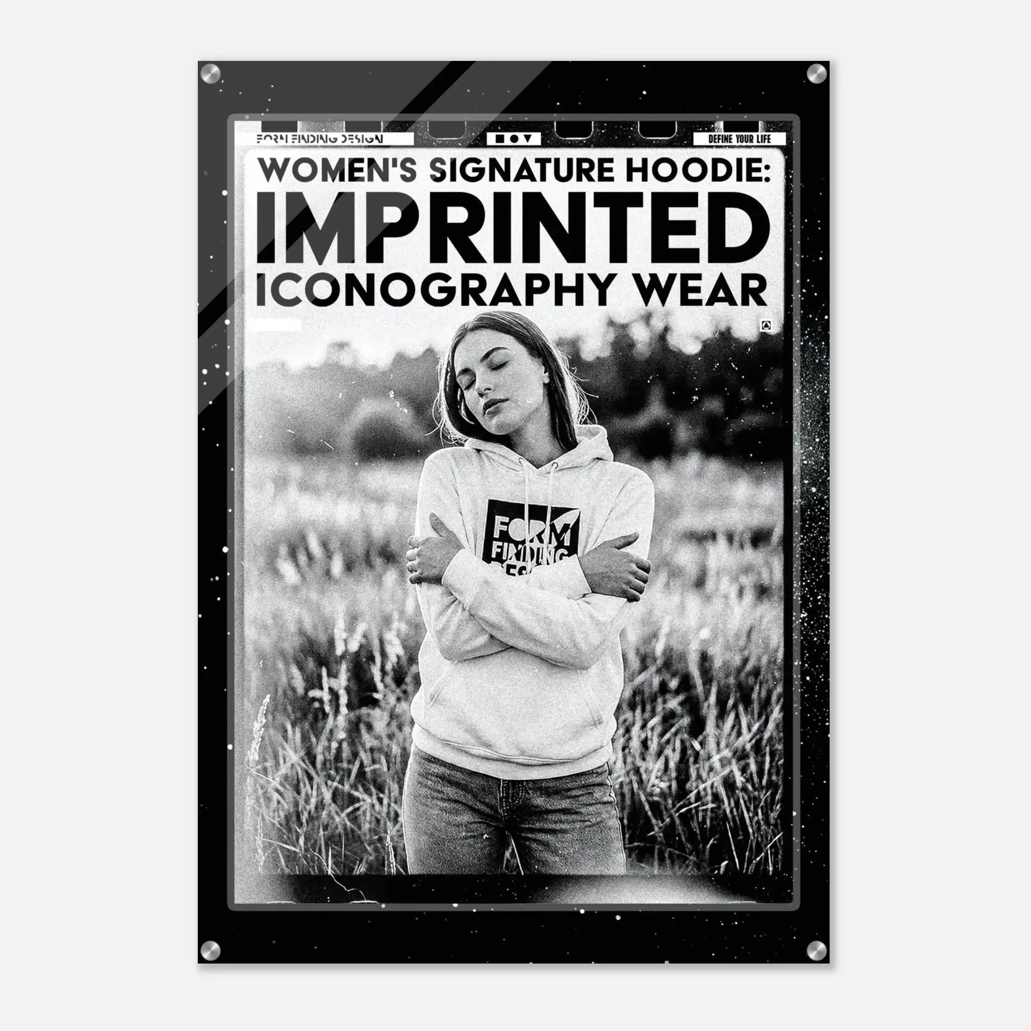 A black-framed art print or poster featuring a black-and-white photograph of a woman in a hoodie standing in a field, with bold text at the top reading 'WOMEN'S SIGNATURE HOODIE: IMPRINTED ICONOGRAPHY WEAR.'.