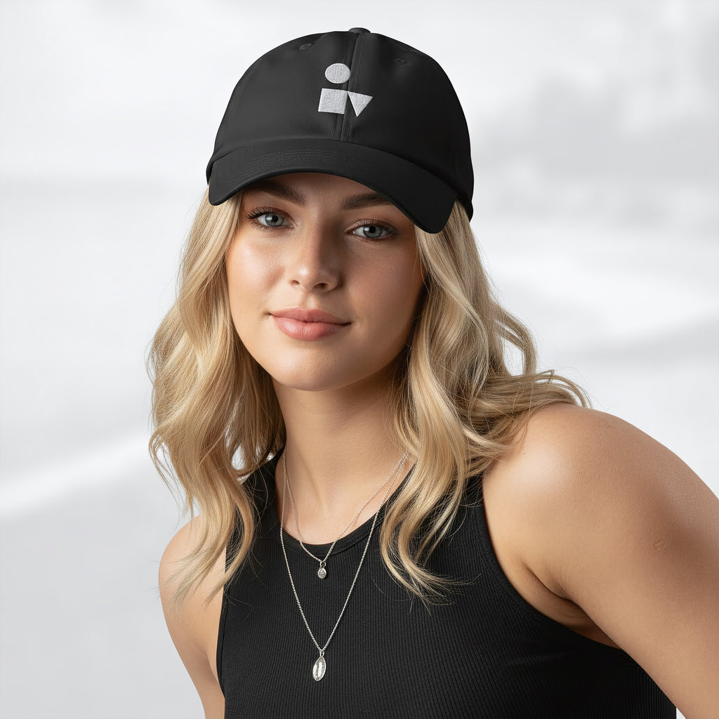 Female model wearing the black Under Armour x Form Fundamentals Stamp Cap (No.06); front view of the cap with white geometric emblem and curved brim, paired with a black tank top and layered necklaces against a softly blurred background.