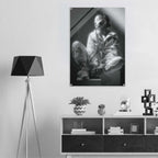 A black and white art print depicting a seated figure in a dramatic interior, displayed on a light gray wall above a modern white and dark wood cabinet, next to a black tripod floor lamp.