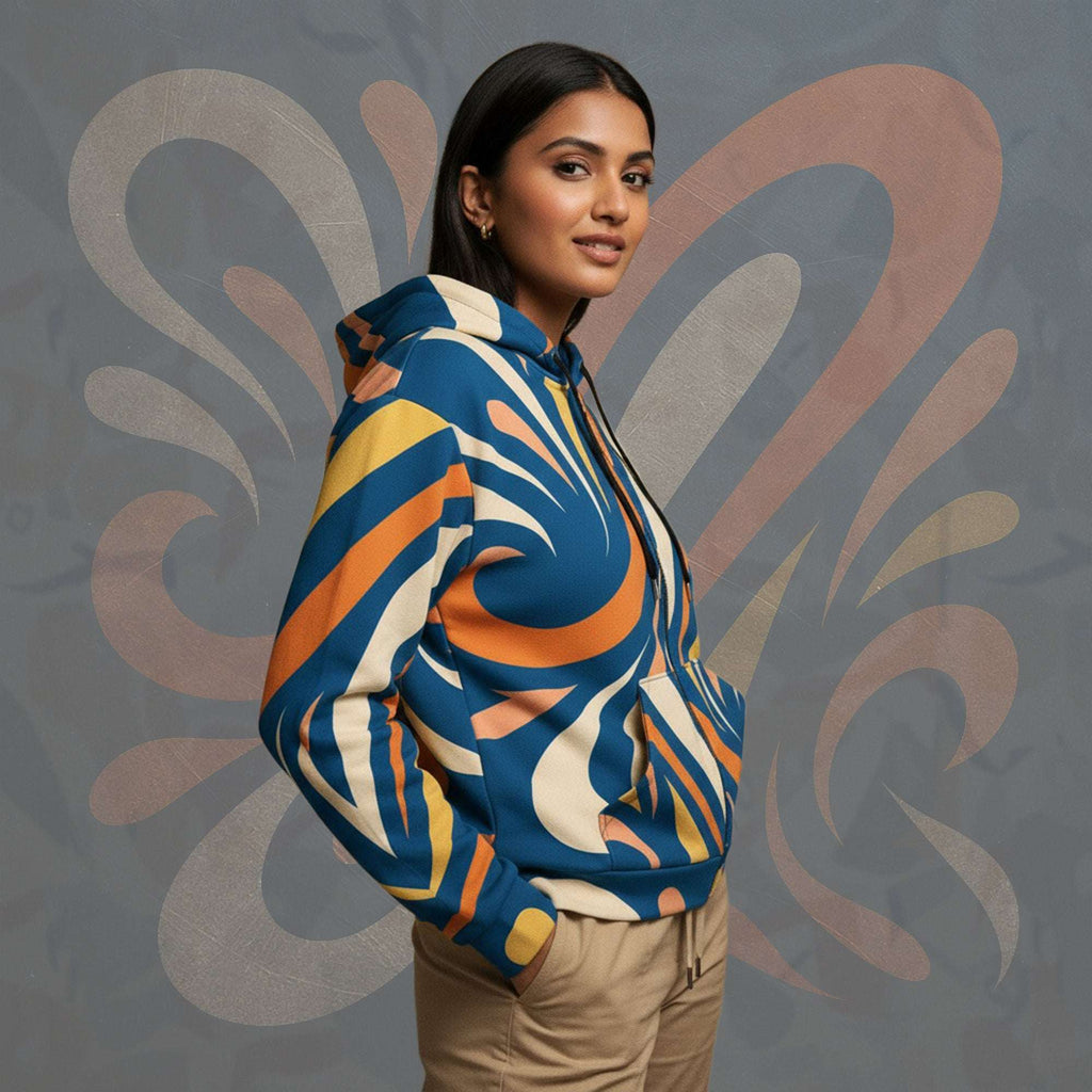 Side lifestyle portrait of model wearing FormFD Women’s Coral Canvas Hoodie (No.17)—zip-through hoodie with hood/sleeves and vibrant coral orange, teal blue, cream and yellow swirl artwork; split kangaroo pocket; textured graphic wall behind.