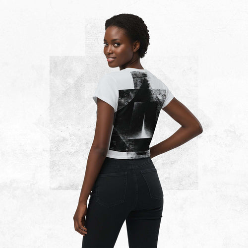 Rear view of model in Form Finding Design Women’s Era Stamp (No.12) crop tee; black-and-white distressed geometric print wraps the back and sleeves, styled with black jeans on a pale white background.