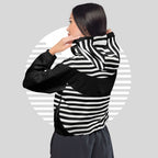 Model wearing black colourway ICN Cropped Windbreaker—three-quarter back pose showing hood and wraparound monochrome stripe graphic, cropped hem with adjustable drawcord from Form Finding Design.