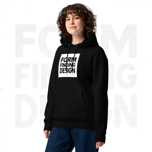 Model wearing black Form Finding Design Women’s Signature Hoodie (FFD-15), three-quarter front—bold white square logo print centred on chest, relaxed fit, soft grey studio backdrop.