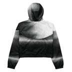 Back studio view of the HER Cropped Dither Distortion Windbreaker, showing the hood and cropped silhouette. The digital distortion print runs from light grey at the upper back to deep charcoal at the hem; the hood’s outer panels are colour‑blocked in black and white, and the elasticated hem is cinched with a drawcord, all set against a clean white backdrop